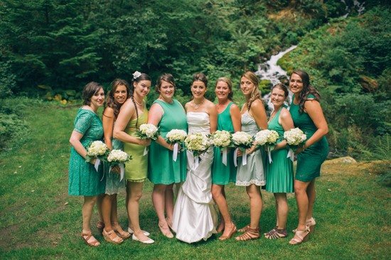 Bridesmaids in green dresses pose with the bride on a wedding day