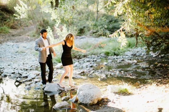Couple crossing a river holding hands in a romantic setting