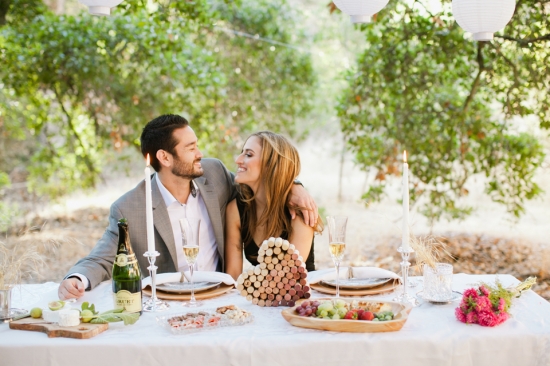 Romantic couple enjoys a picnic with champagne, outdoors in the nature
