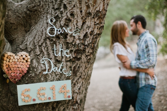 Romantic couple and Save the Date sign on a tree trunk