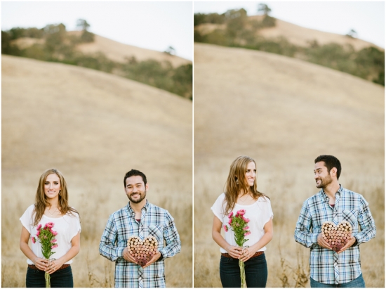 Happy couple holding flowers and heart shaped decoration in nature