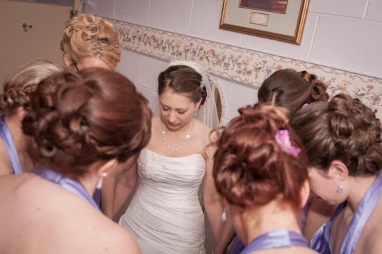Bride surrounded by bridesmaids before wedding ceremony