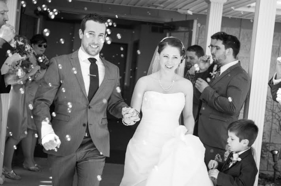 Newlyweds exit wedding surrounded by bubbles black and white