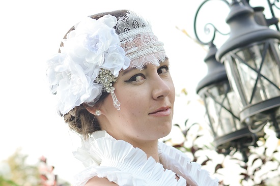 Elegant woman in a white dress and flower headpiece looking at camera