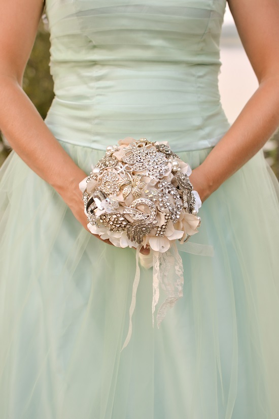 Bride holding a unique brooch bouquet in an elegant mint dress