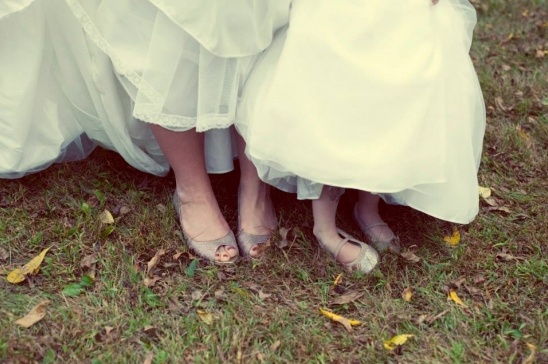 Bride and flower girl in white dresses, wearing elegant silver shoes