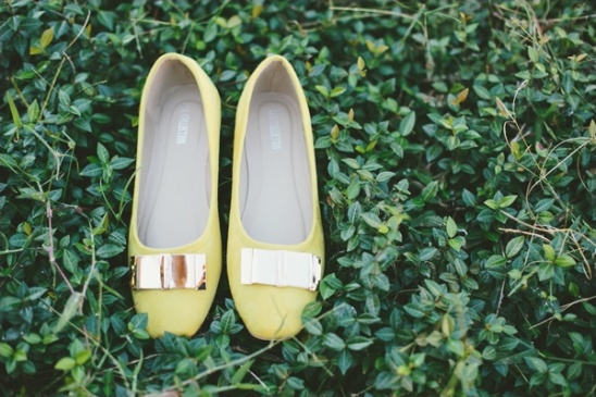 Yellow ballet flats with gold buckles on green foliage