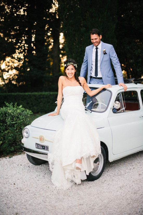 Happy wedding couple with a vintage Italian car