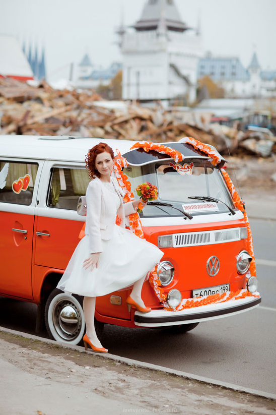 Bride in white dress by orange VW bus