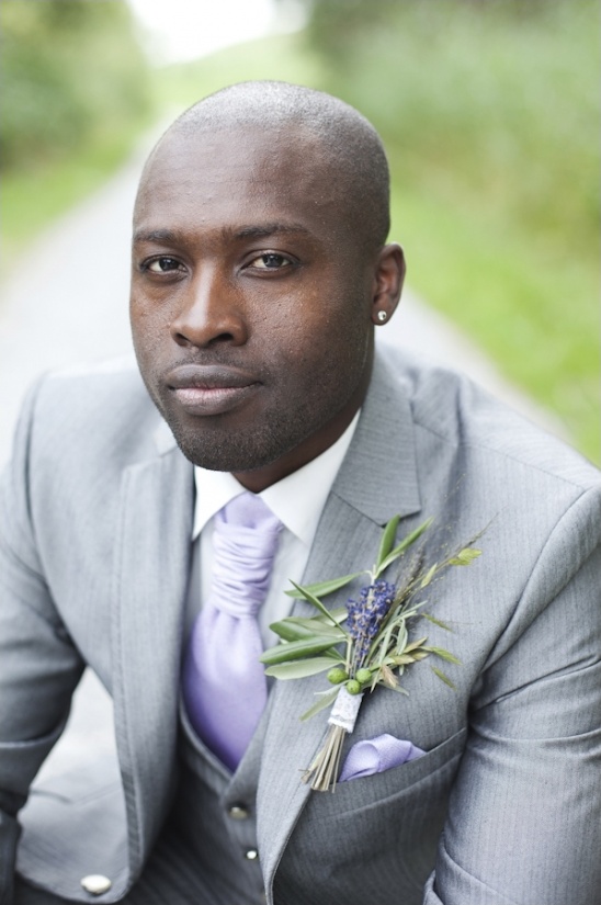Handsome groom in a gray suit with lavender boutonniere