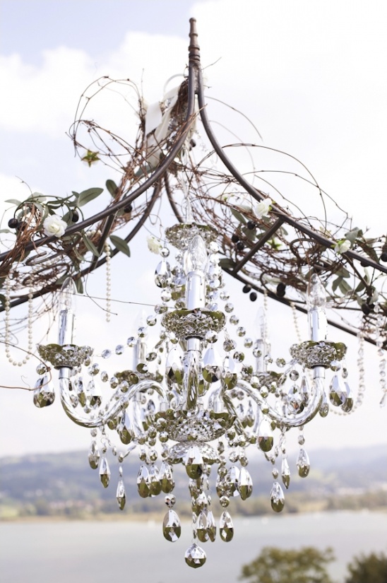 Elegant crystal chandelier hangs outdoors with floral accents