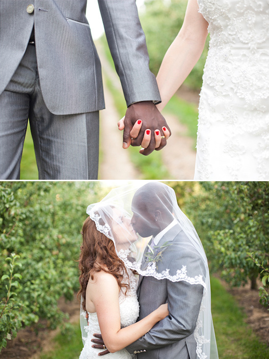 Interracial couple holding hands and kissing at wedding