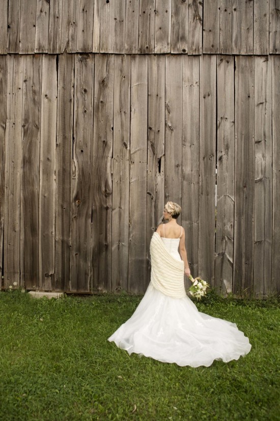 Bride in elegant wedding dress by rustic barn