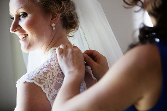 Bride getting ready with bridesmaid adjusting her dress