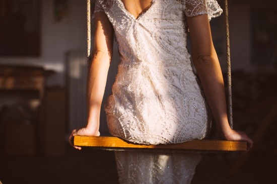 Woman in vintage lace dress sitting on wooden swing