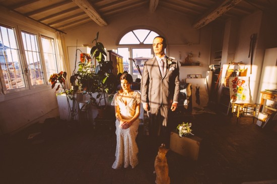 Sunlit wedding couple in art studio with dog