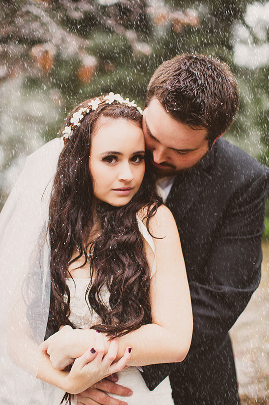 Bride and groom embrace in the rain on their wedding day