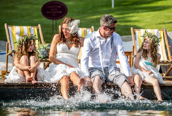 Bride groom and flower girls splash feet in lake water