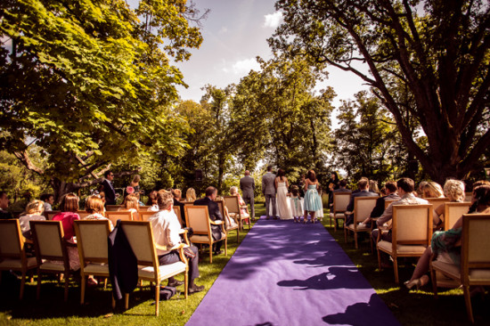Outdoor garden wedding ceremony with purple aisle runner