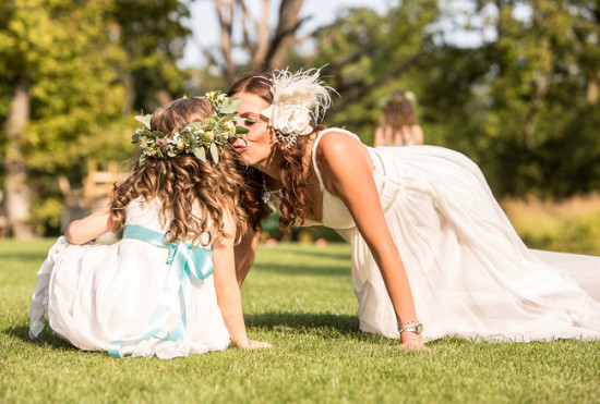 Bride kissing a flower girl during an outdoor wedding ceremony