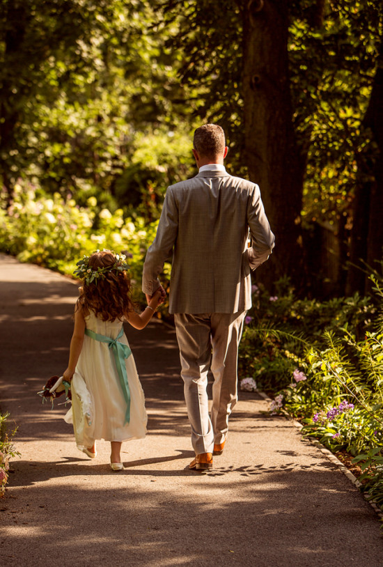 Father and daughter walking hand in hand on a sunlit path