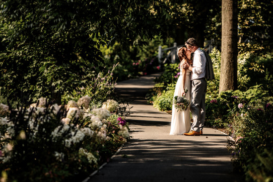 Wedding couple sharing a kiss on a garden path, romantic moment