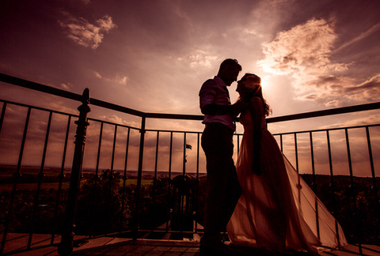 Romantic couple silhouette at sunset on balcony with cloudy sky