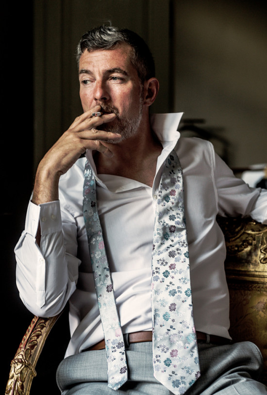 Contemplative man with floral tie smokes cigarette