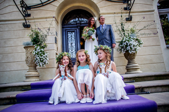 Joyful flower girls sit on purple steps at wedding