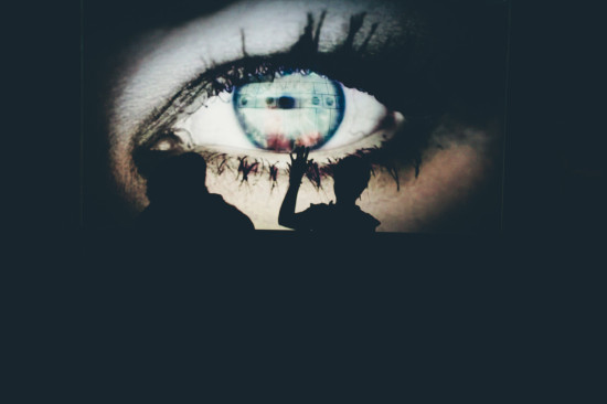 Giant eye projection with silhouetted figures