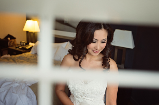 Bride gazes down in white wedding dress indoor shot