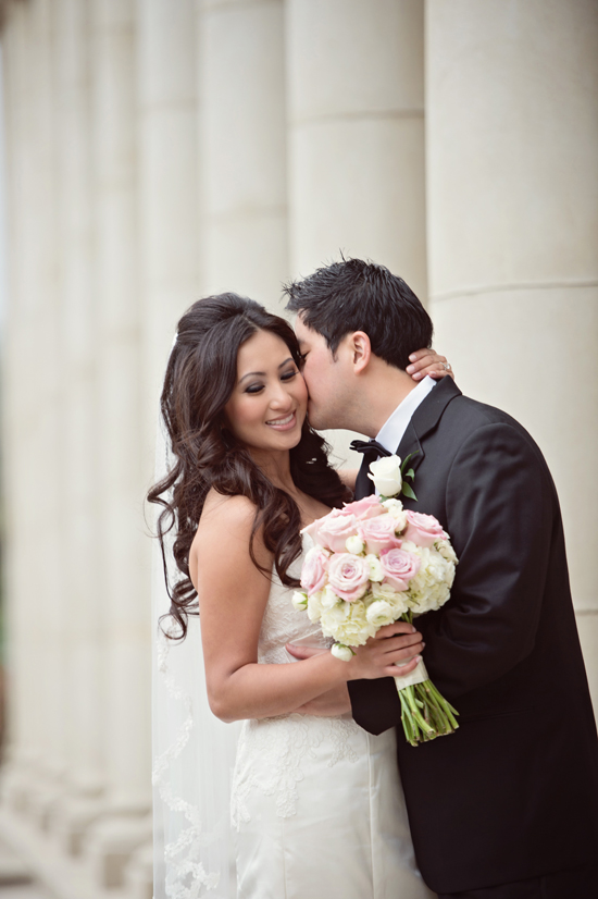 Bride and groom kissing on wedding day with flower bouquet