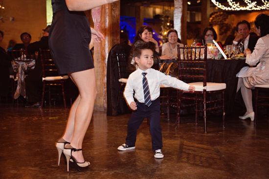 Boy dances at a wedding reception with woman in heels