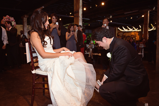 Groom putting on brides garter at wedding reception