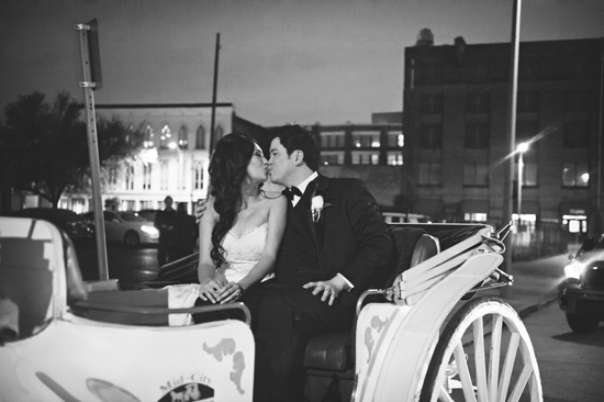 Newlyweds share a romantic kiss in a horse drawn carriage