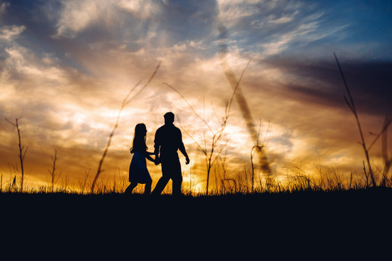 Silhouette of father and daughter walking at sunset