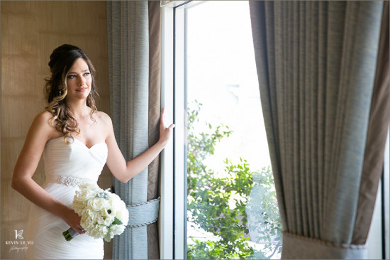 Bride gazes out window with wedding bouquet in hand