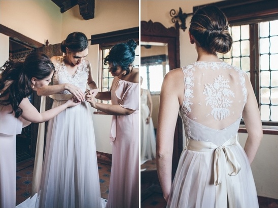 Bride getting ready in lace back wedding dress with bridesmaids