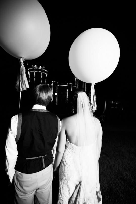 Wedding couple holding hands with large balloons at night