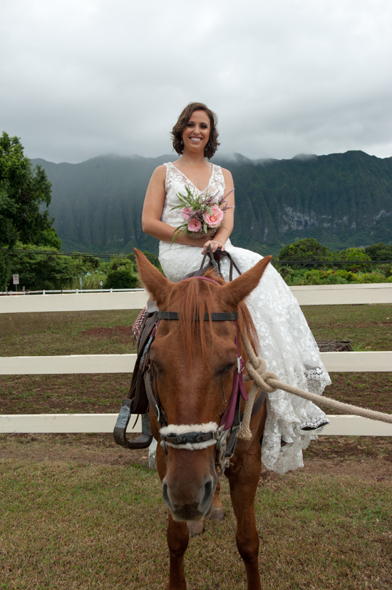 Bride in wedding dress riding horse outdoors