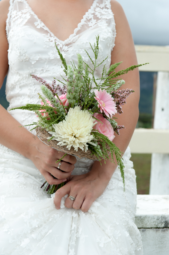 Bride in lace dress holds wildflower wedding bouquet