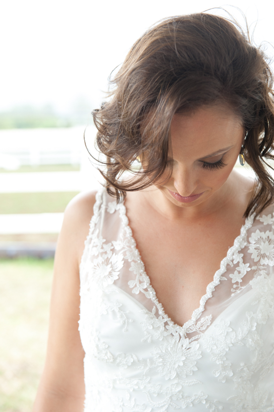 Bride in lace wedding dress looking down softly