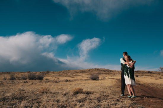 Couple embracing outdoors with blue sky and dramatic clouds