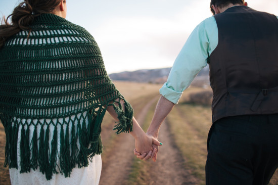 Newlyweds stroll holding hands on a rural road at sunset