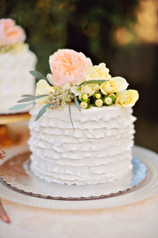 ruffled white wedding cake with floral topper