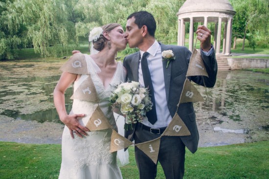 Bride and groom kissing, holding wedding bunting