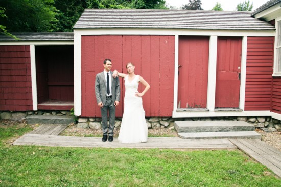 Happy couple posing by red barn on their wedding day