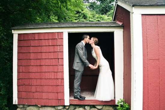 Bride and groom kissing in red barn doorway