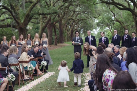 Children walk down aisle at outdoor wedding ceremony