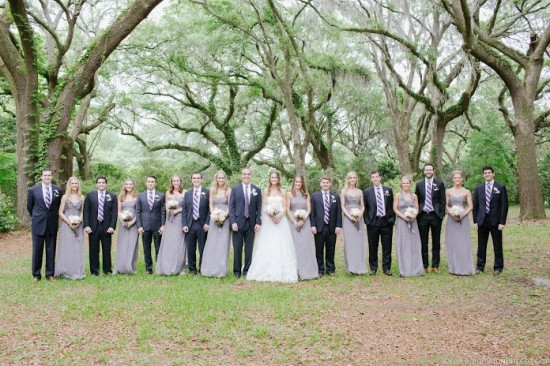 Wedding party poses under oak trees in formal attire